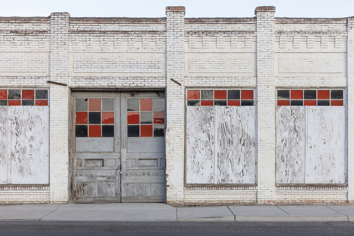 Aging commercial building with boarded-up windows, worn exterior, and visible signs of deferred maintenance.