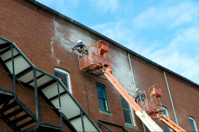 horizontal-photo-of-two-workers-re-pointing-bricks-2026-03-26-06-48-38-utc (1) Aging commercial building with boarded-up windows, worn exterior, and visible signs of deferred maintenance.