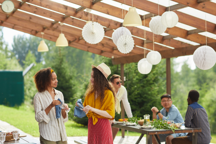 Friends enjoying food and conversation in a covered outdoor living space designed for entertaining guests.